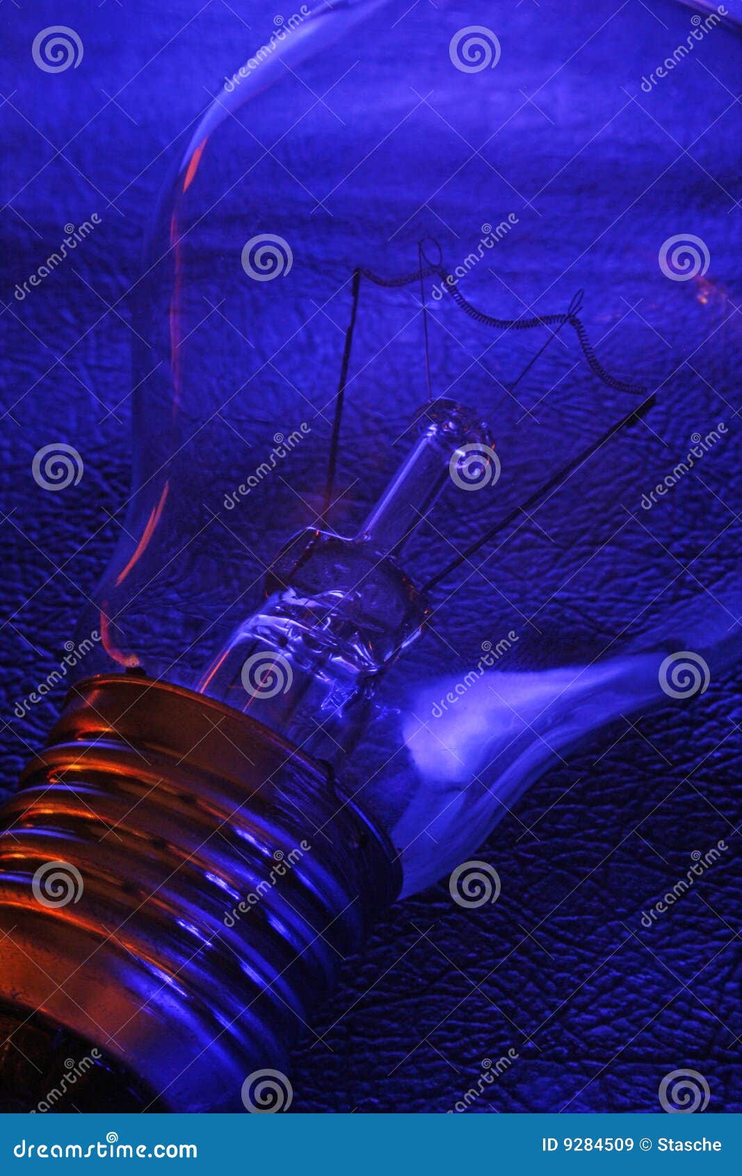 Classical Electric Tungsten Light Bulb on a Textured Blue Background with Red Highlights on the