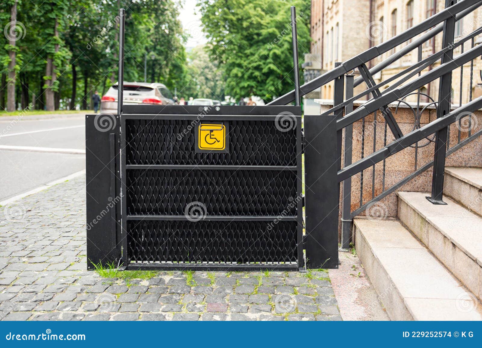 electric platform lift at building staircase for disabled people with wheelchair sign plate on old city street. elevator