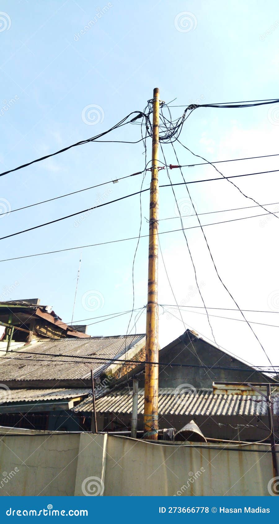 Electric Pole in Front of the House with Bright Clouds As a Background