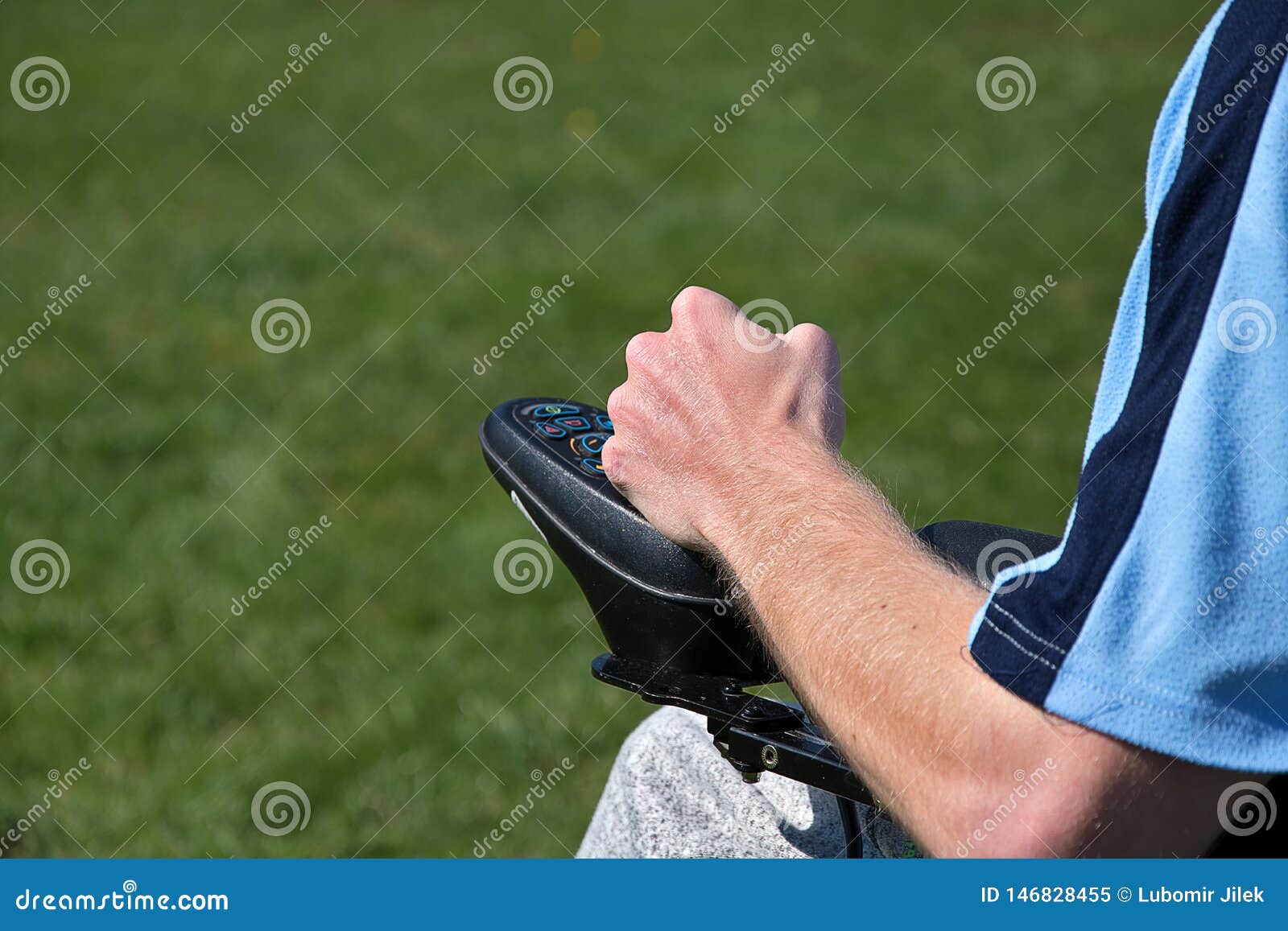 Electric Wheelchair. Young Man Controls a Wheelchair with His Left Hand