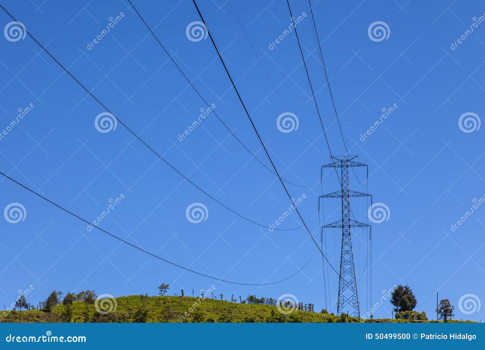 electrical powerlines on a hill before a blue sky
