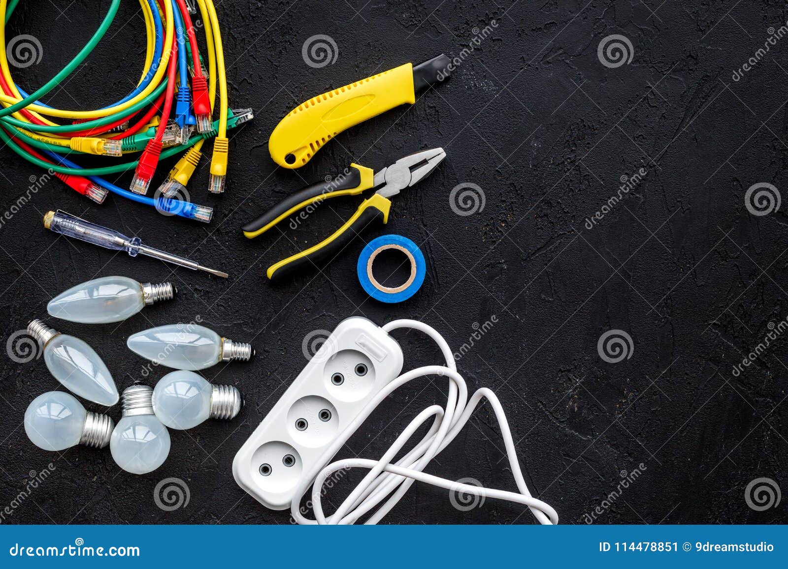 Electrical repair. Bulbs, socket outlet, cabel, screwdriver, pilers on black background top view copy space. Electrical repair. Bulbs screwdriver pilers top view.