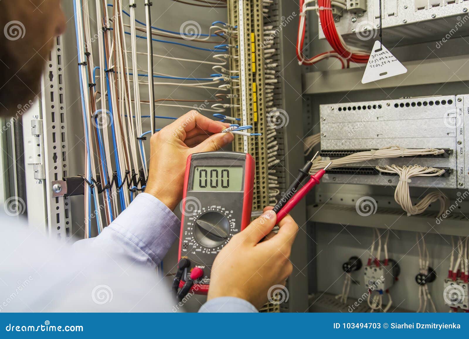 Electrician Engineer with Multimeter Tests Electrical Control Panel of