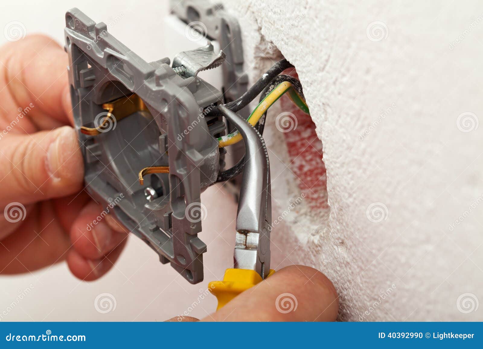 Electrician Hands Installing Wires into Electrical Outlet Stock Photo