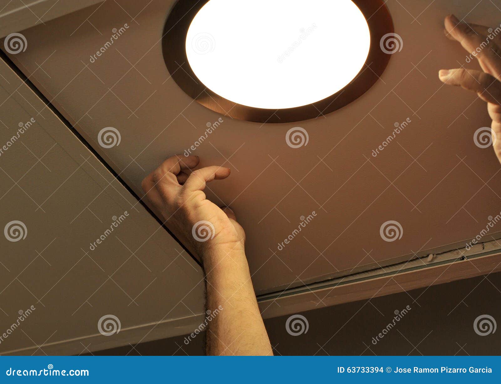 Electrician Installing a Spotlight in the Kitchen Ceiling Stock Photo
