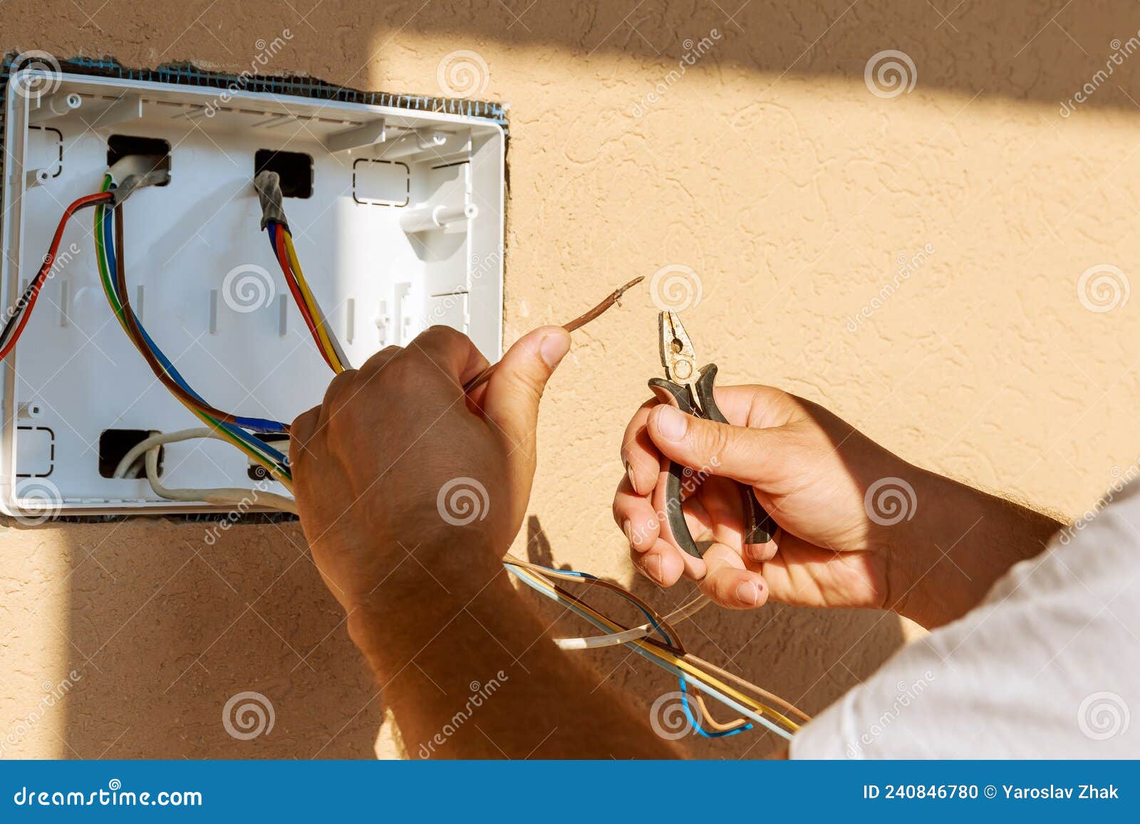 an electrician repairs an electrical wire for connecting an electrical panel.