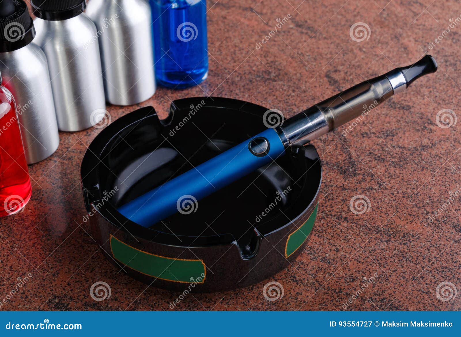 Electronic Cigarette on the Ashtray and Bottles with Vape Liquid on