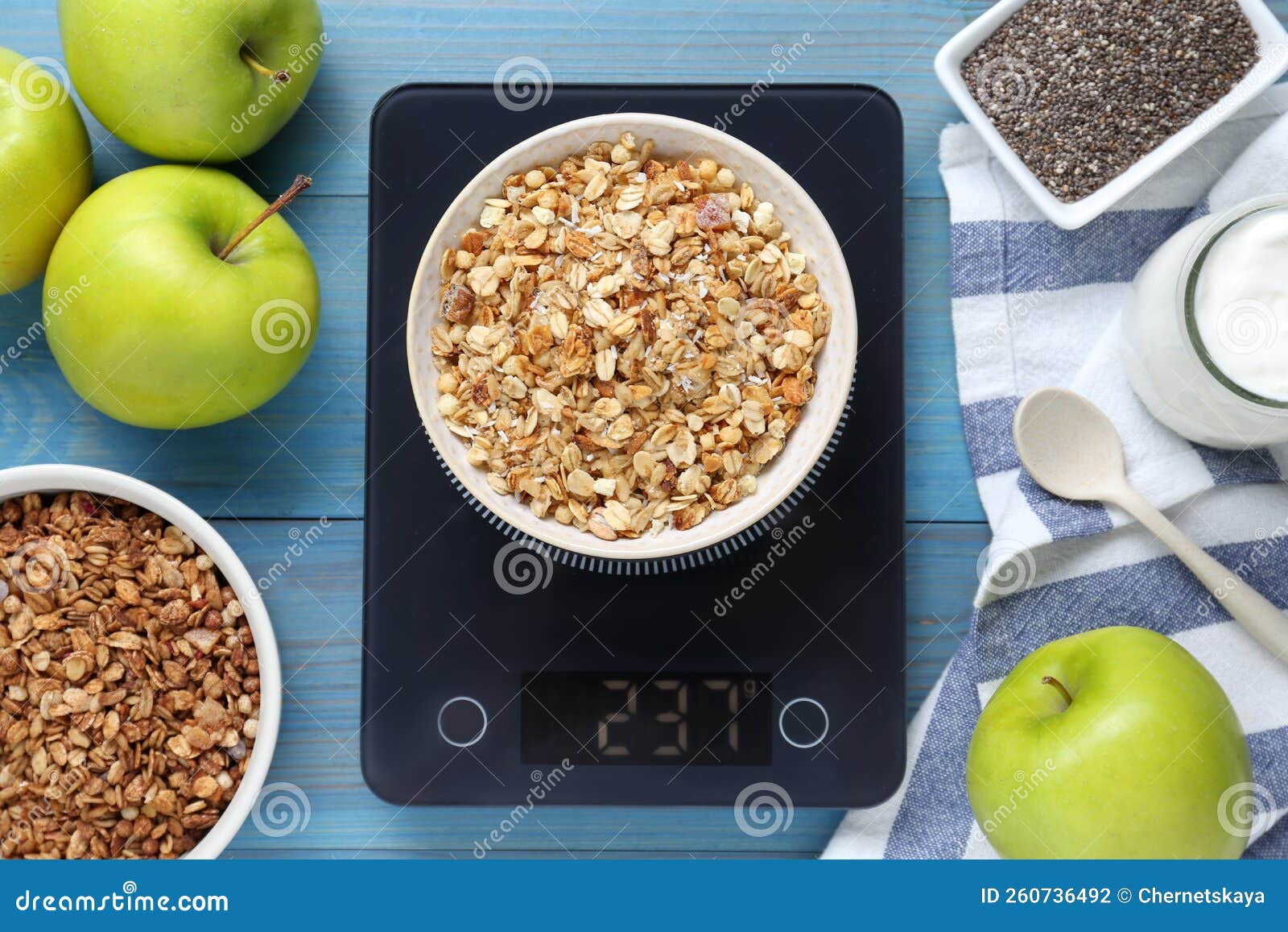 electronic scales with granola and different products on light blue wooden table, flat lay