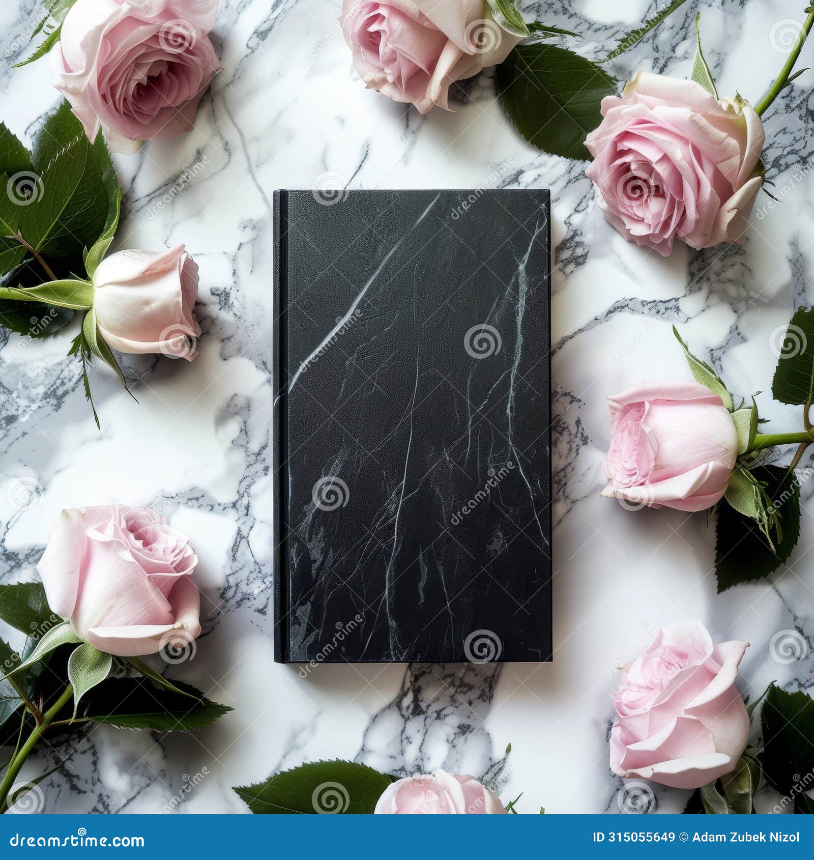elegant black notebook surrounded by pink roses on a marble surface