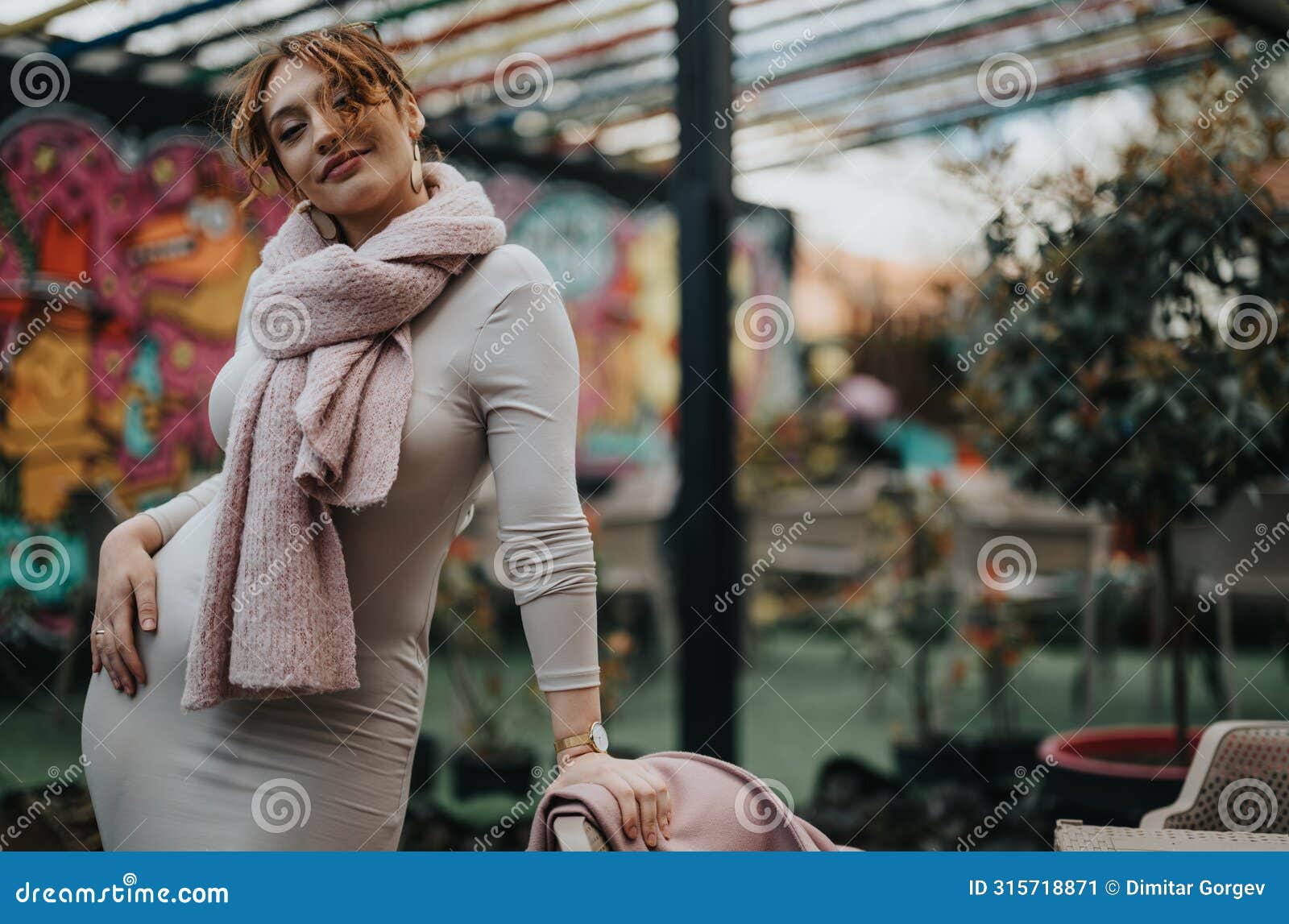 elegant businesswoman with a stylish pink scarf and coat at a cafe