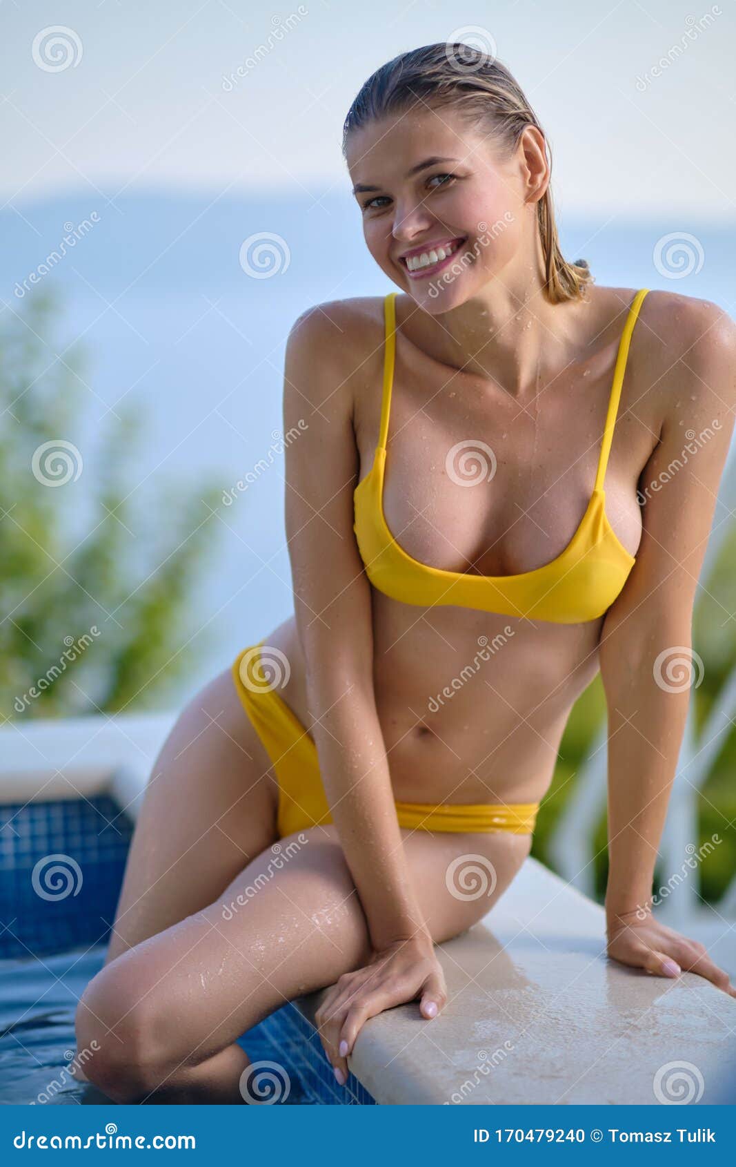 sexy woman in bikini on the sun-tanned slim and ly body is posing near the swimming pool