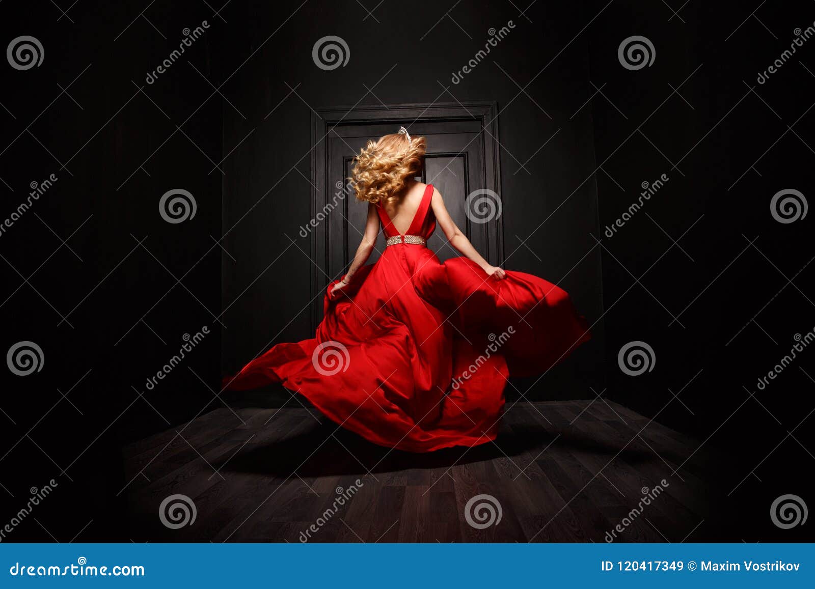 elegant and woman in the red evening fluttering dress is capture in move, running away from the ceremony