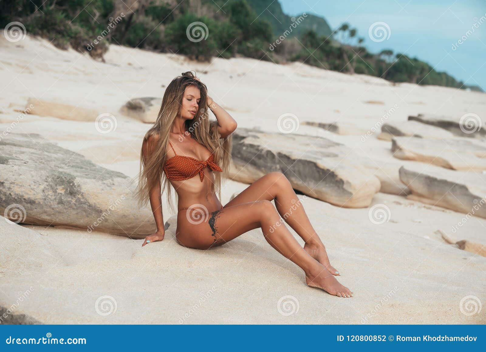 Sexy Girl with Large Breasts Sits on the Sand and Sensually