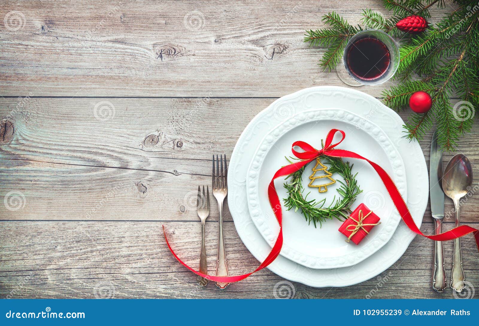 Elegante servida de la tabla de cena dispuesto con las decoraciones de la Navidad, la guirnalda del romero y la caja de regalo