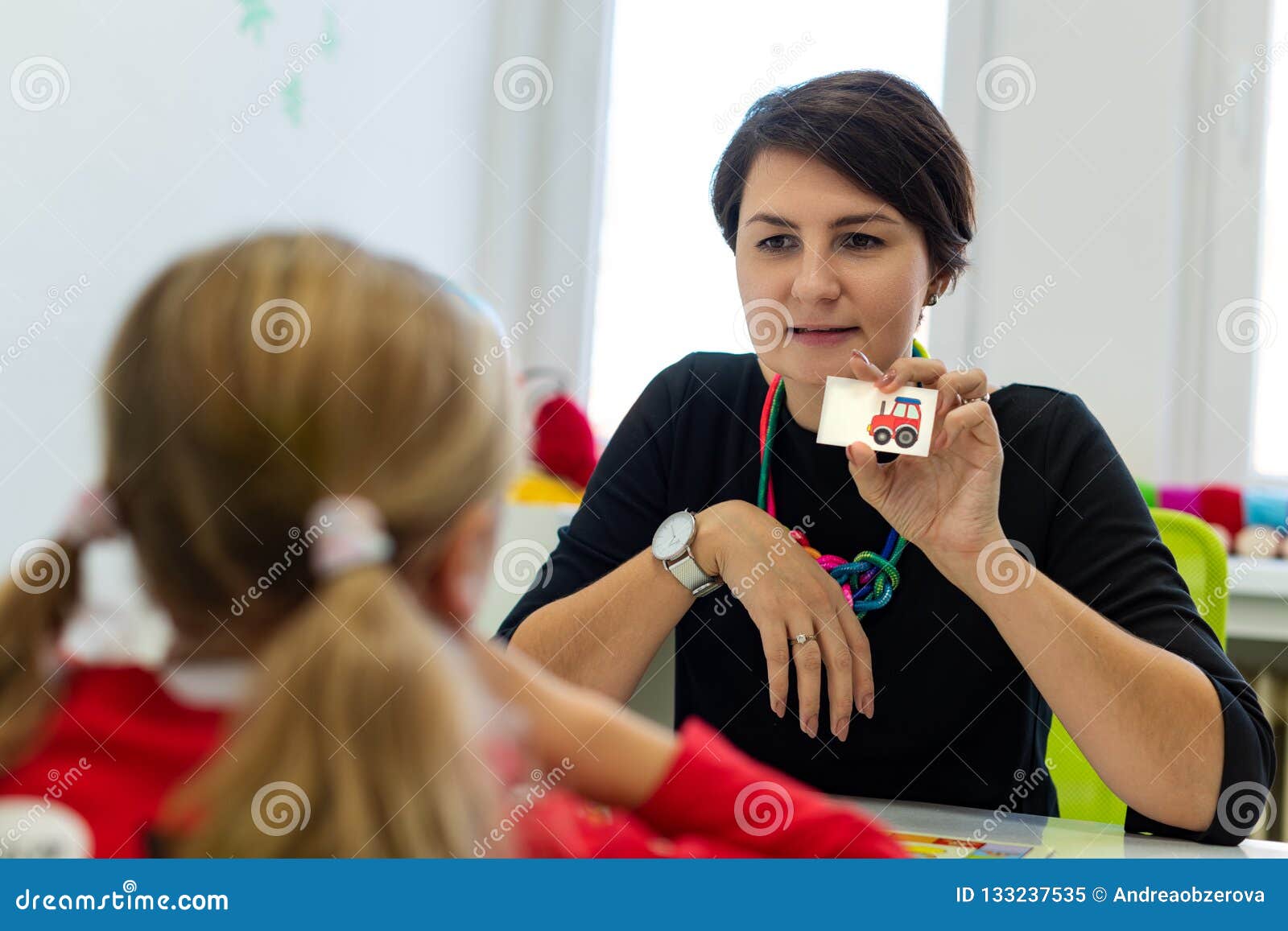 ary age girl in child occupational therapy session doing playful exercises with her therapist.