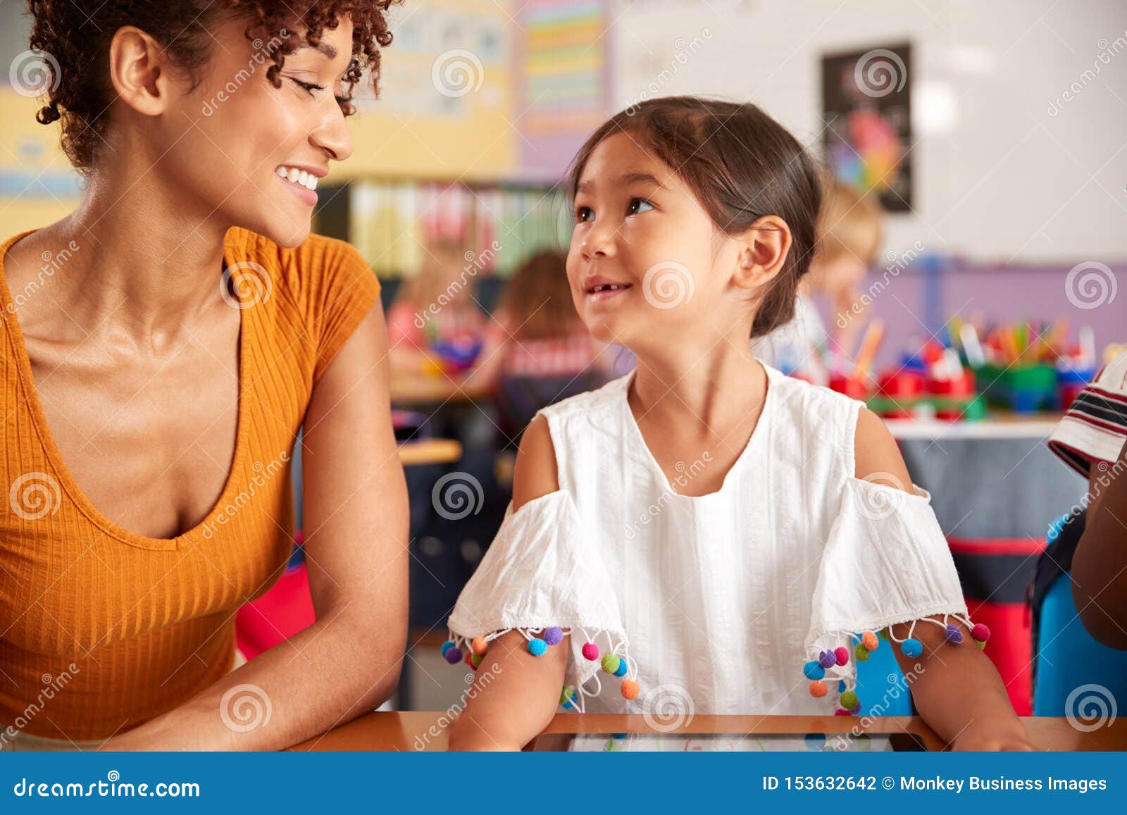 Elementary School Teacher and Female Pupil Drawing Using Digital Tablet