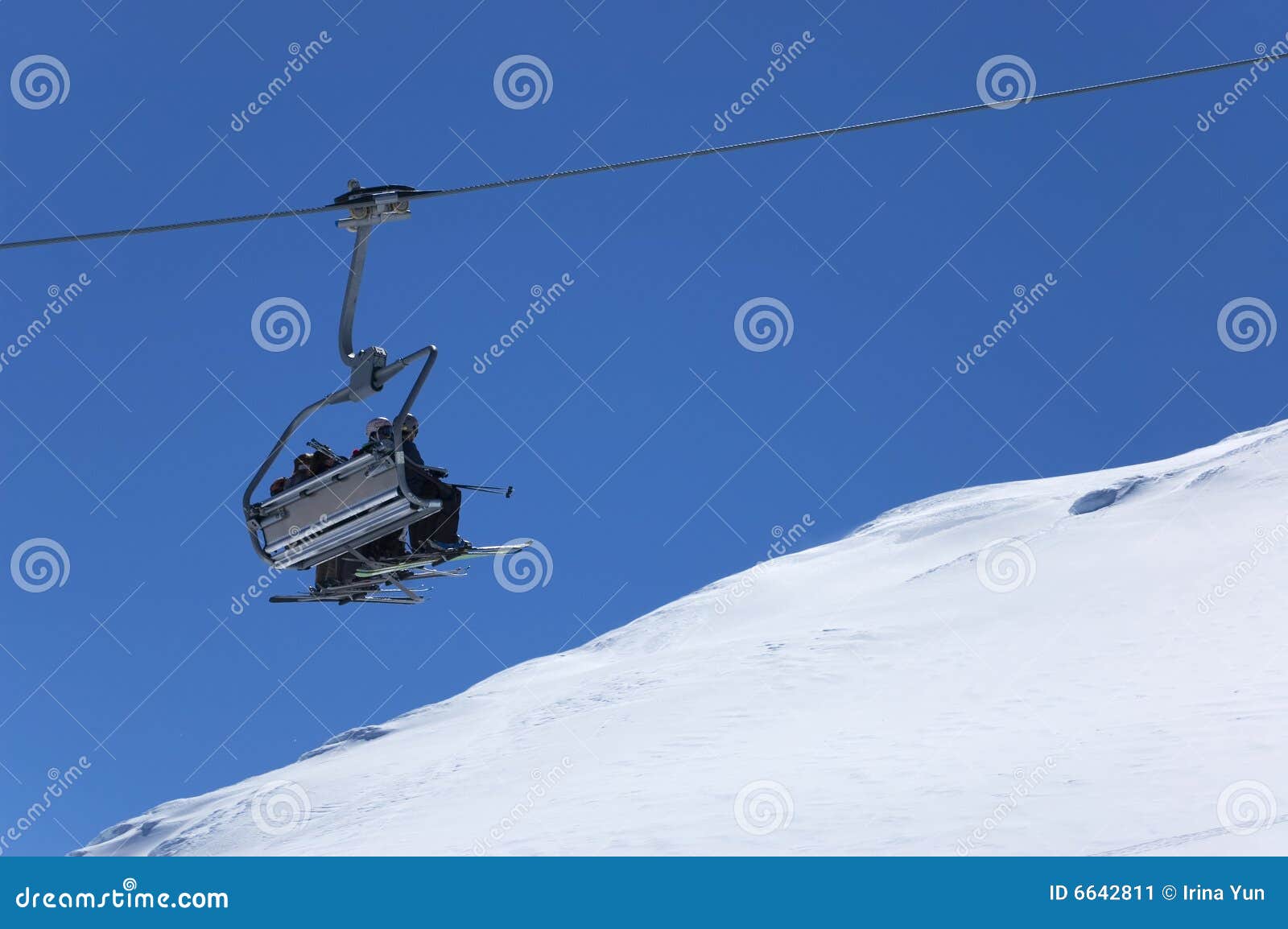 Elevatore di presidenza alla stazione sciistica. Vacanze di inverno. Elevatore di presidenza con gli sciatori che vanno in su alla stazione sciistica. Cielo blu e neve bianca su priorità bassa