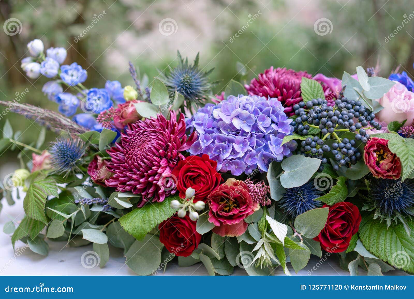 Elongated Floral Arrangement in Vintage Metal Vase. Table Setting. Blue ...