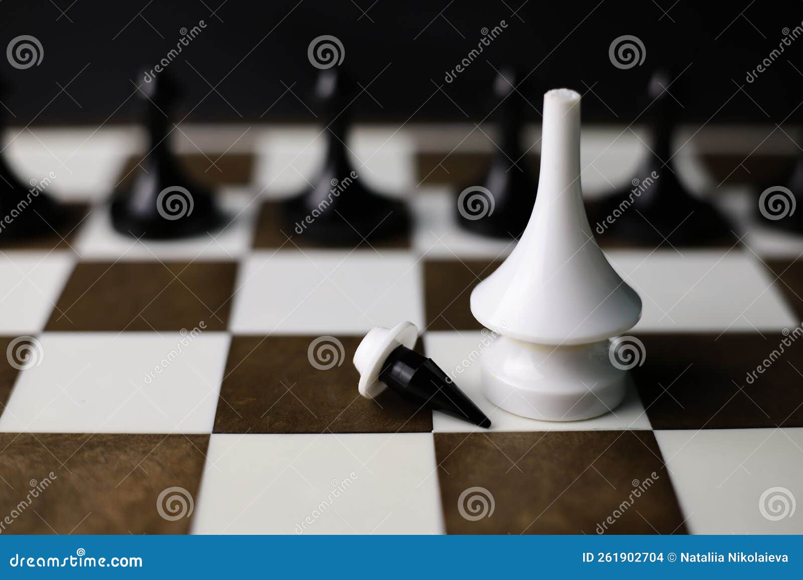 Um jogo de xadrez com um homem em pé sobre um tabuleiro de xadrez com uma  grande peça de xadrez branca ao fundo.