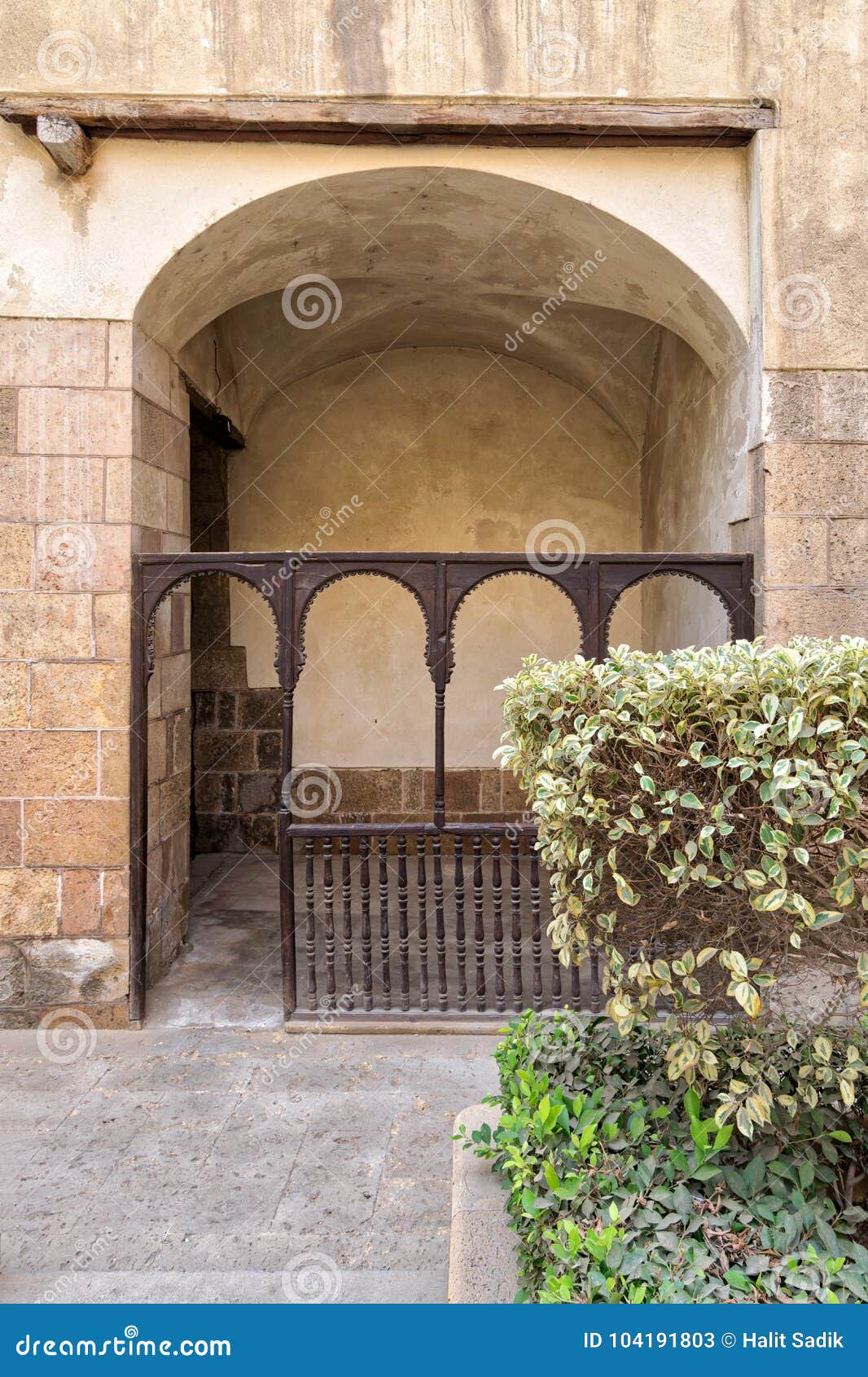 embedded space with wooden balustrade and wooden arches behind a planted flower box at the external wall of an old historic house