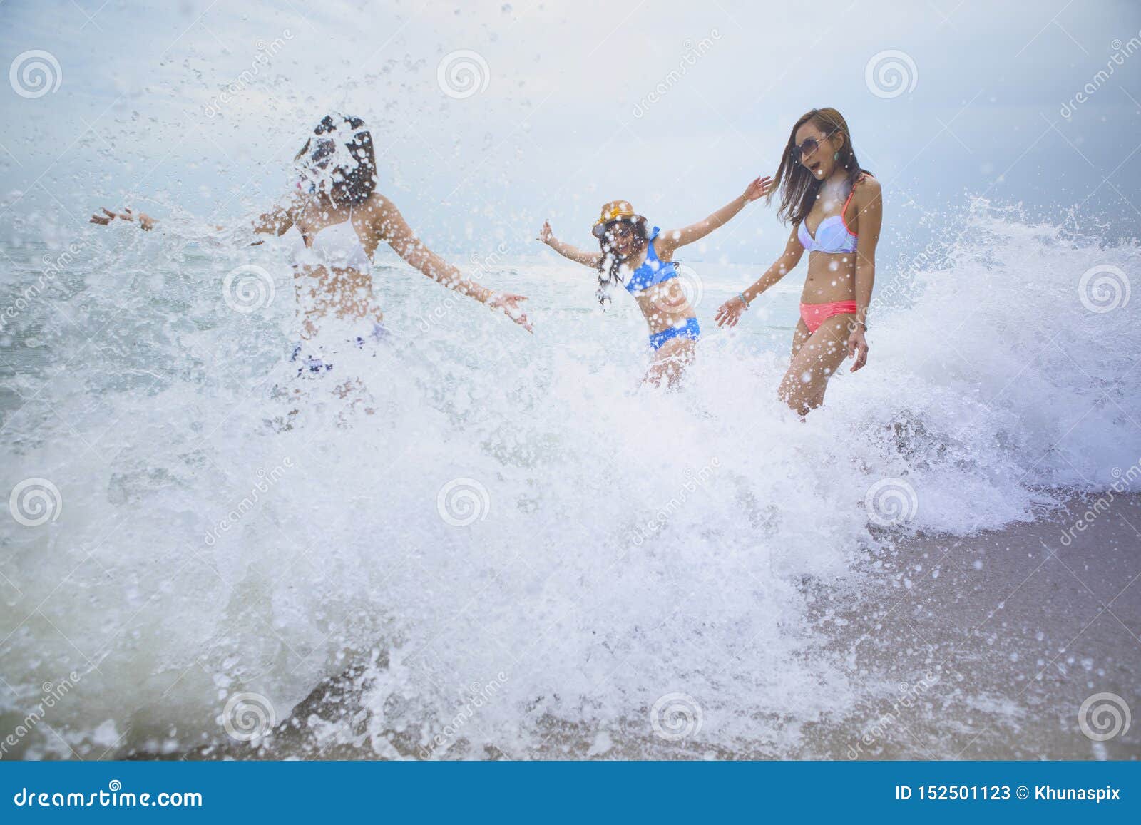 Emoção da felicidade de três mulheres com espirro da onda da praia do mar