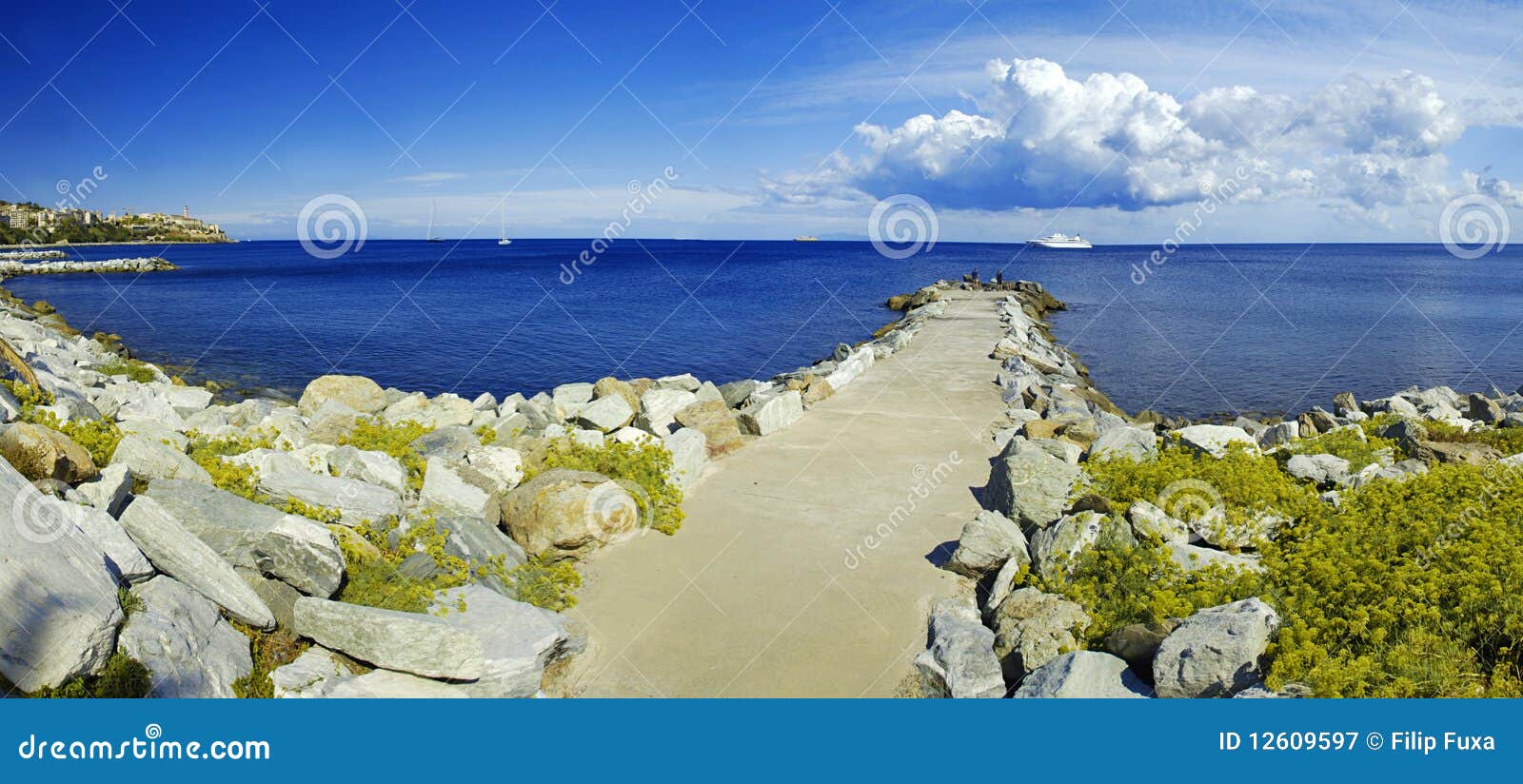 Empiedre el embarcadero y el yate. Embarcadero de piedra largo en Córcega con un yate de lujo en del cielo el panorama amplio posterior y dramático arriba -