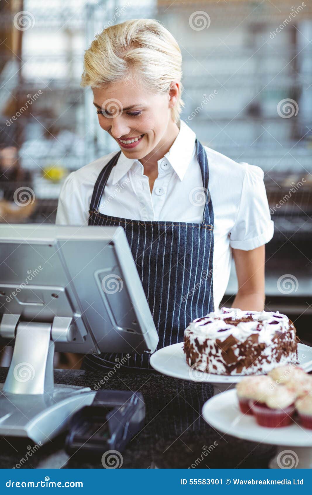 Empleado sonriente que usa la calculadora en contador en la panadería