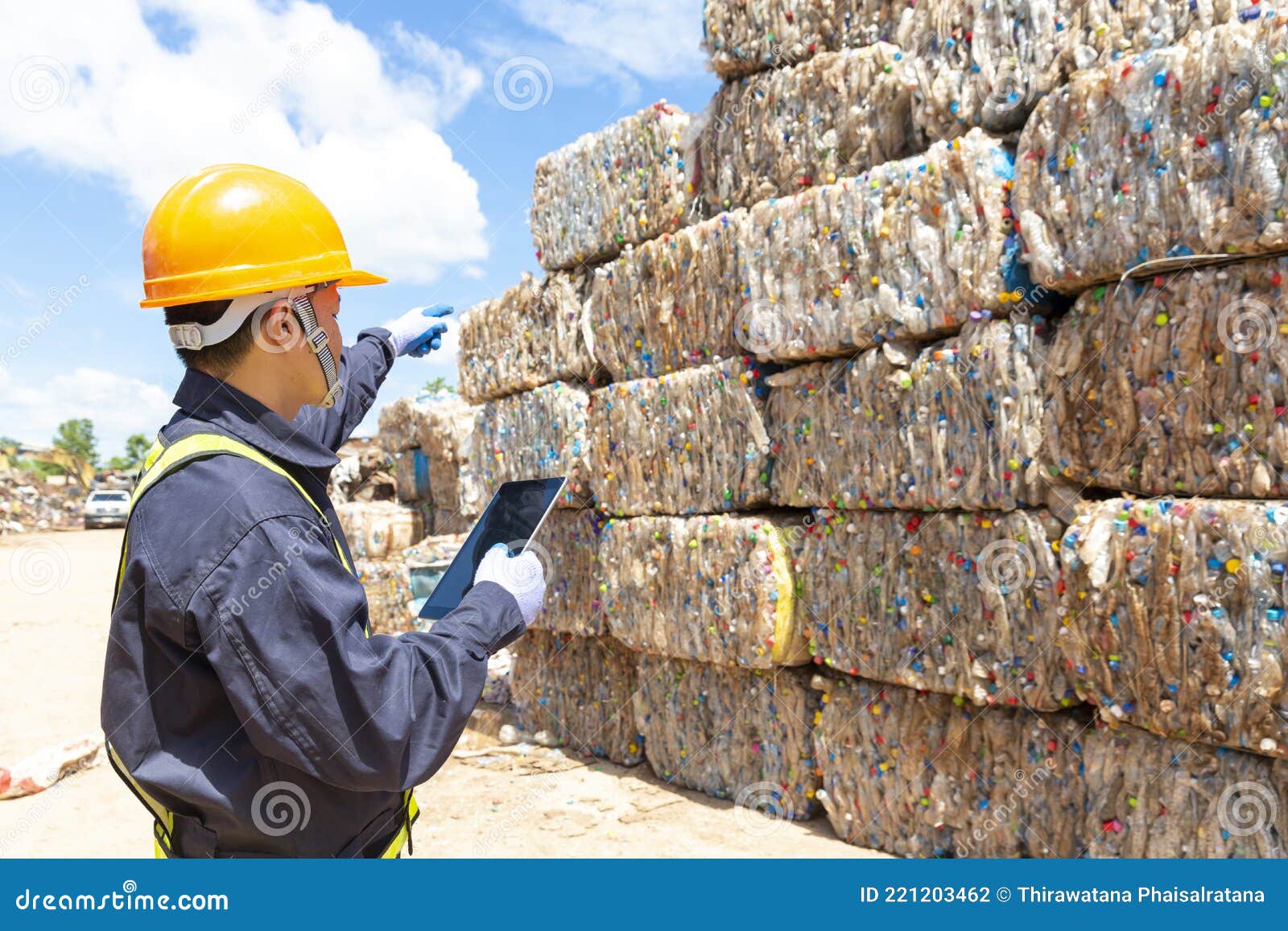 An Employee at a Recycling Plant is Pointing To Plastic Waste Being