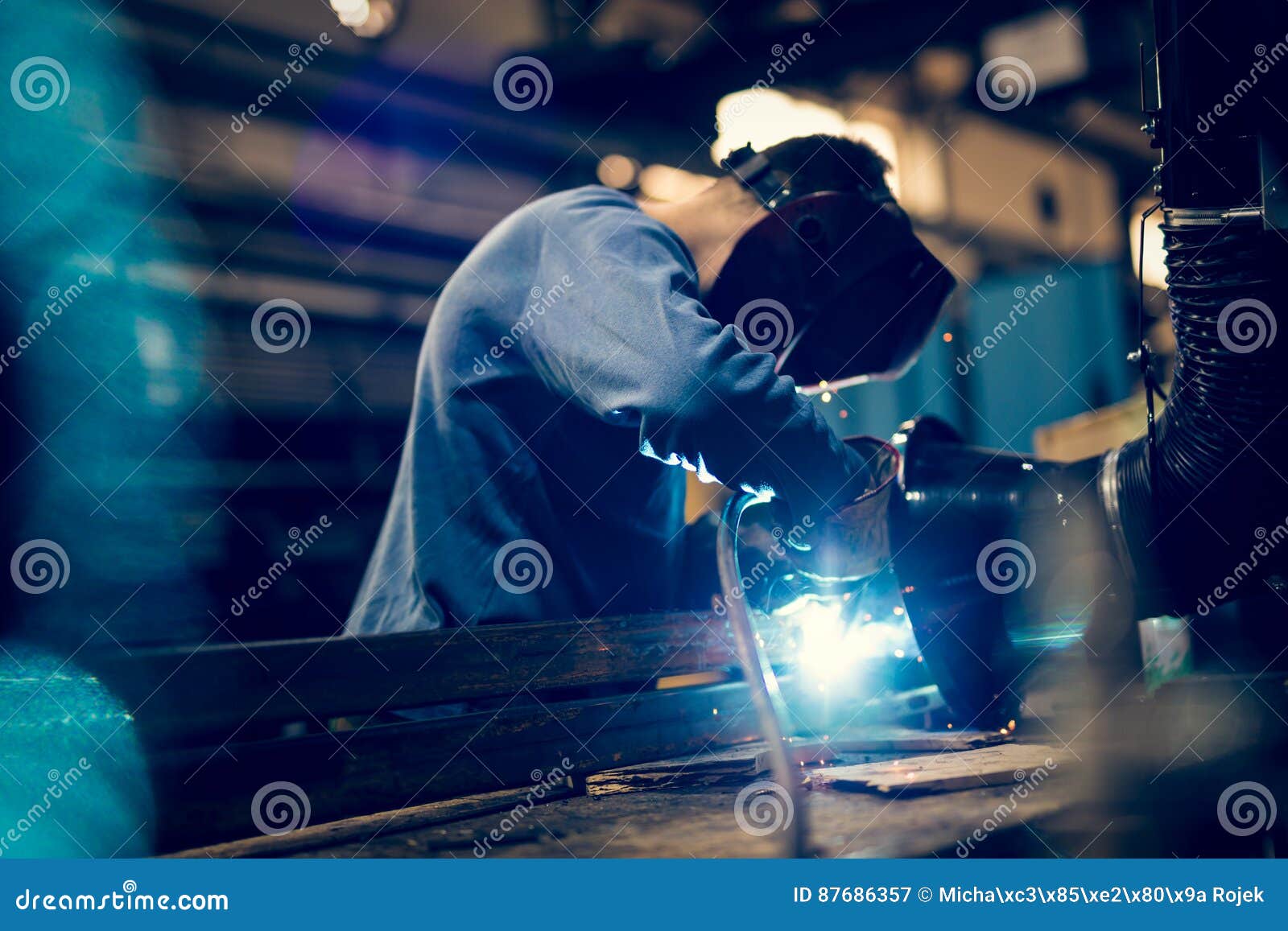 employee welding steel with sparks using mig mag welder