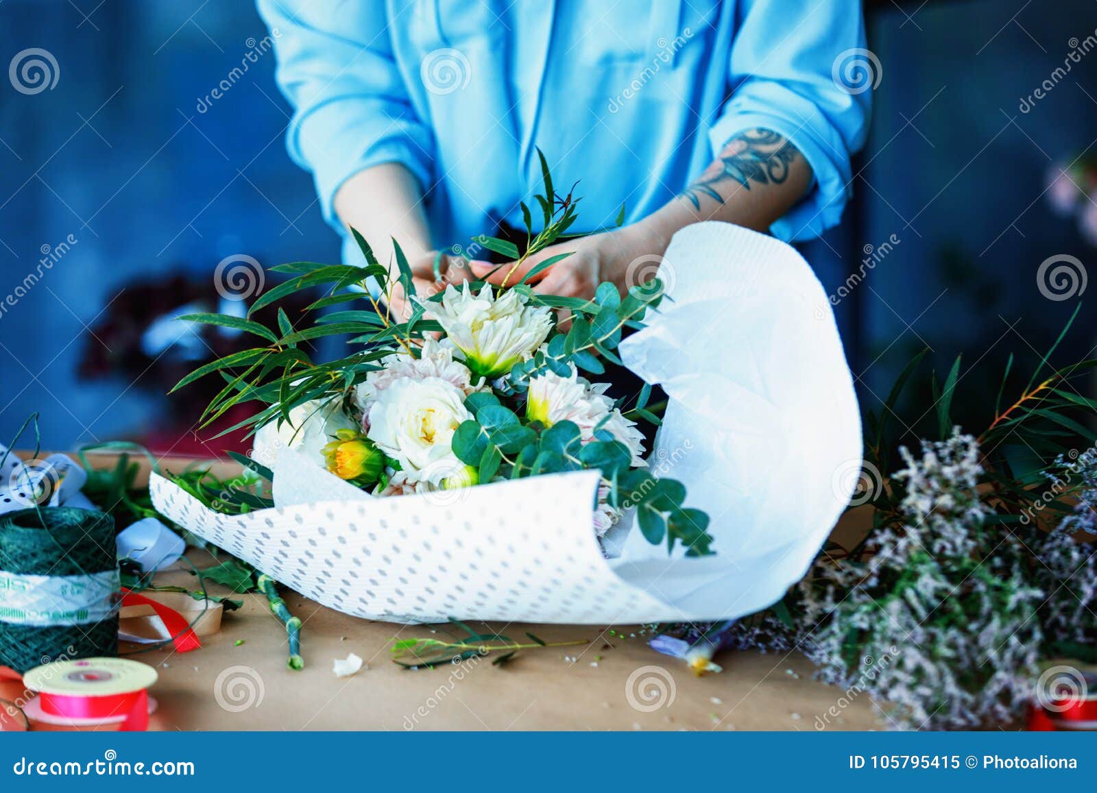 Employé de magasin féminin gai avec du charme faisant le bouquet avec le populus et le chrysanthème poplaraceous Anasta à tête si