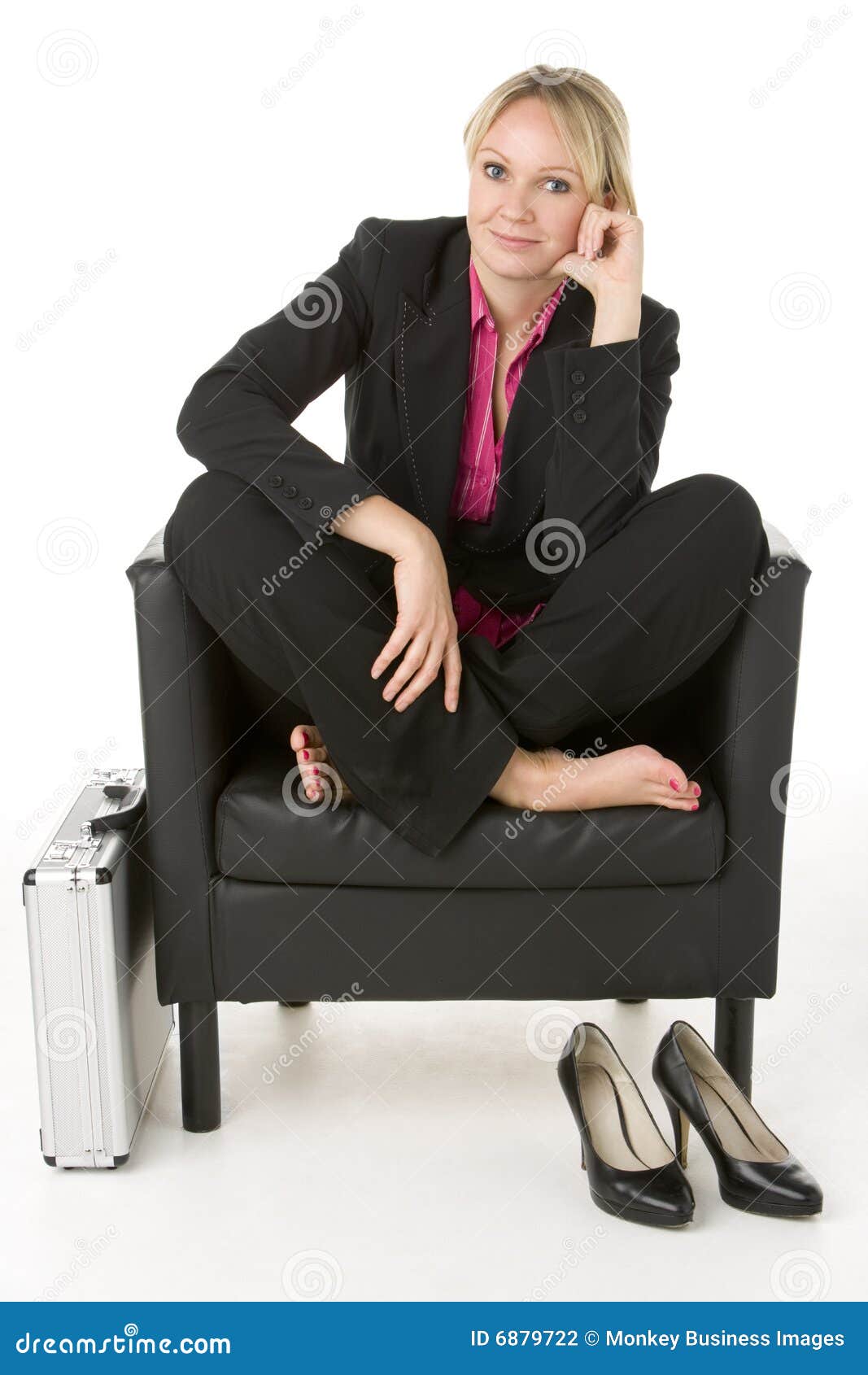 Empresaria que se sienta en la silla de cuero con sus zapatos apagado