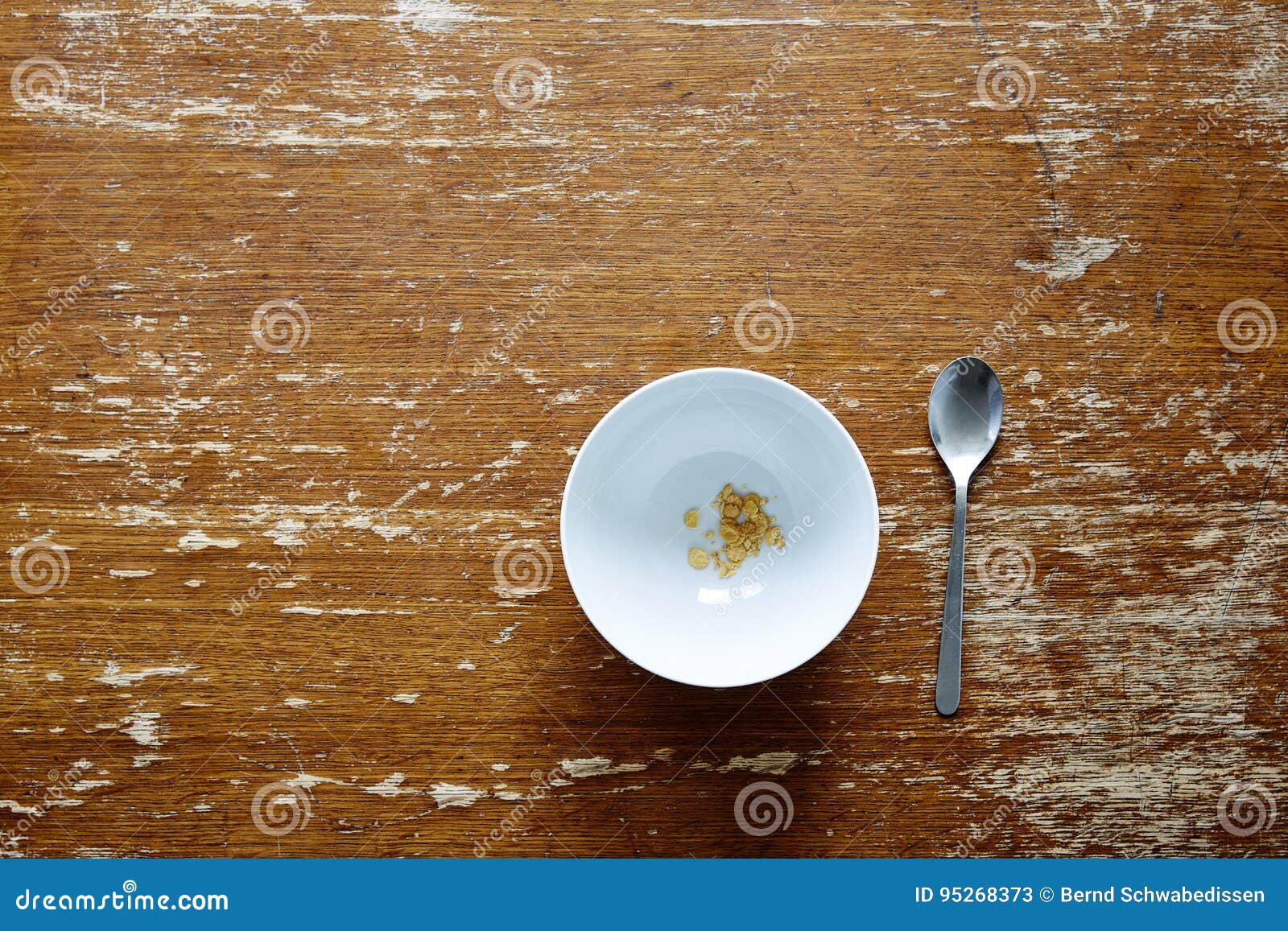 empty bowl with little cereal on dark wooden table