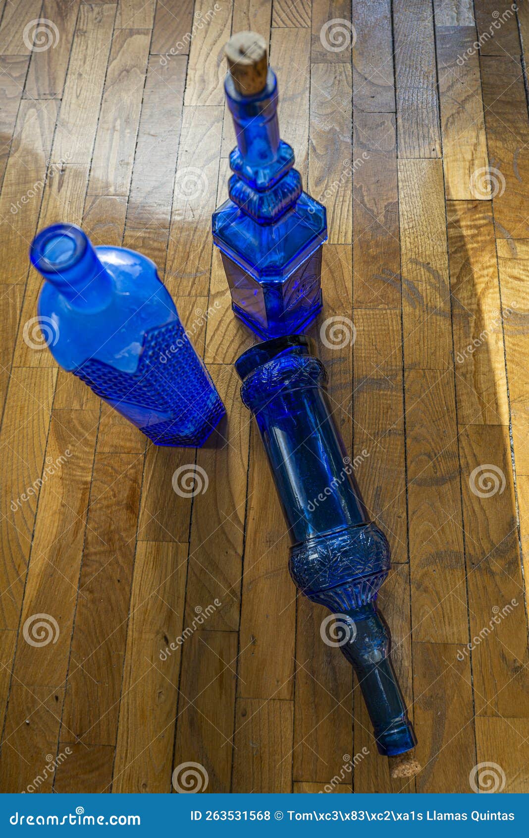 Empty Decorative Blue Glass Bottles on Oak Parquet Surface Stock Photo
