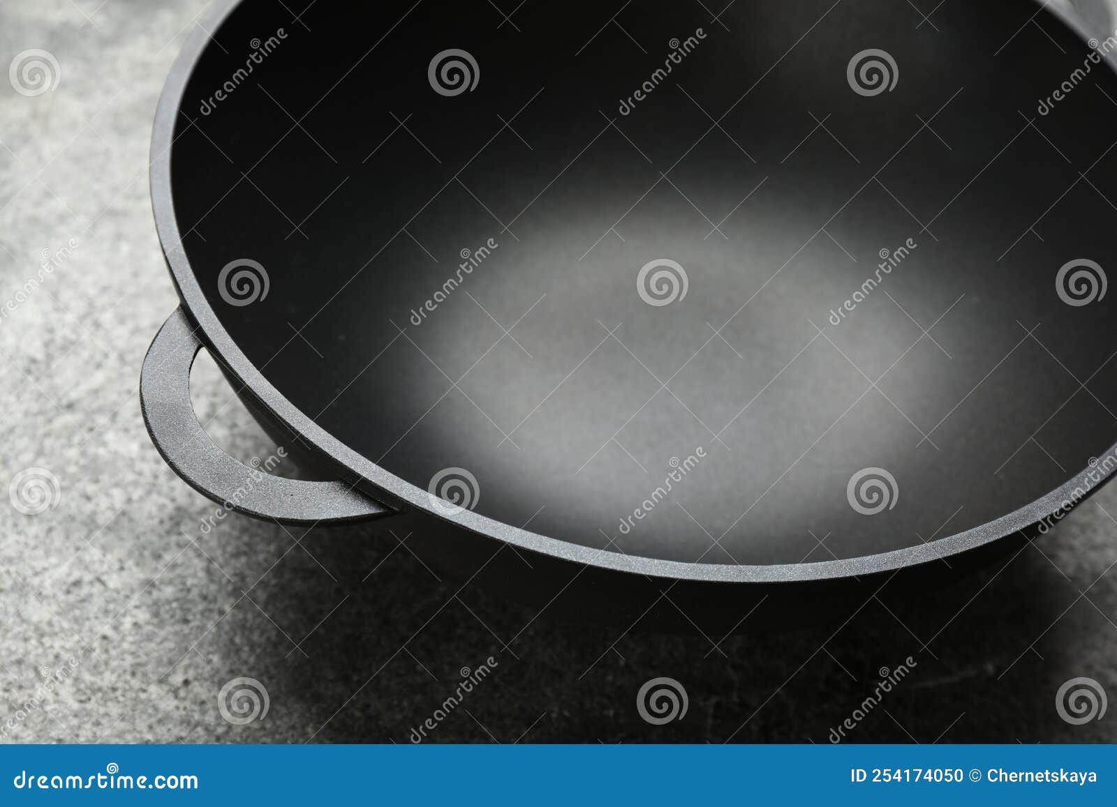Empty Iron Wok on Grey Table, Closeup. Chinese Cookware Stock Photo