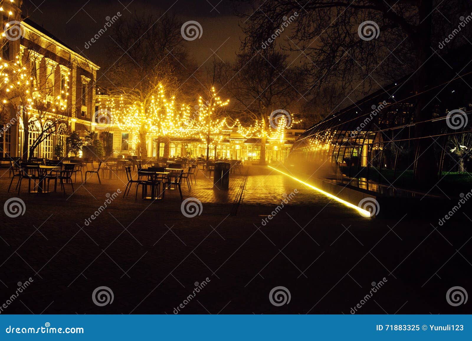 empty night restaurant, lot of tables and chairs with noone, magic fairy lights on trees like christmas