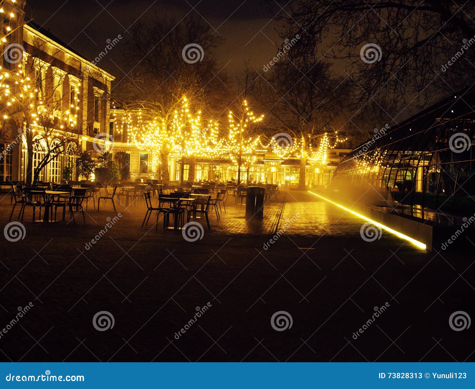 empty night restaurant, lot of tables and chairs with noone, magic fairy lights on trees like christmas, luxury