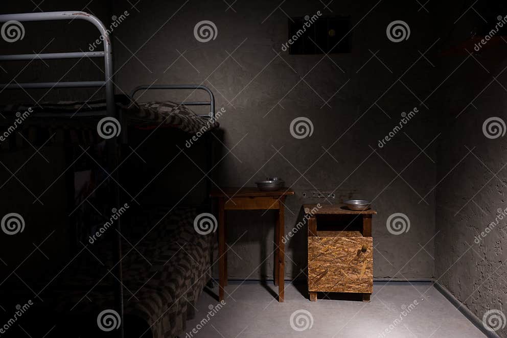 An Empty Prison Cell with Bunk Bed and Bedside Table Stock Photo