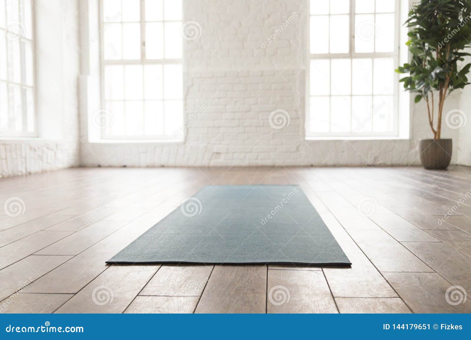 empty room in yoga studio, unrolled yoga mat on floor