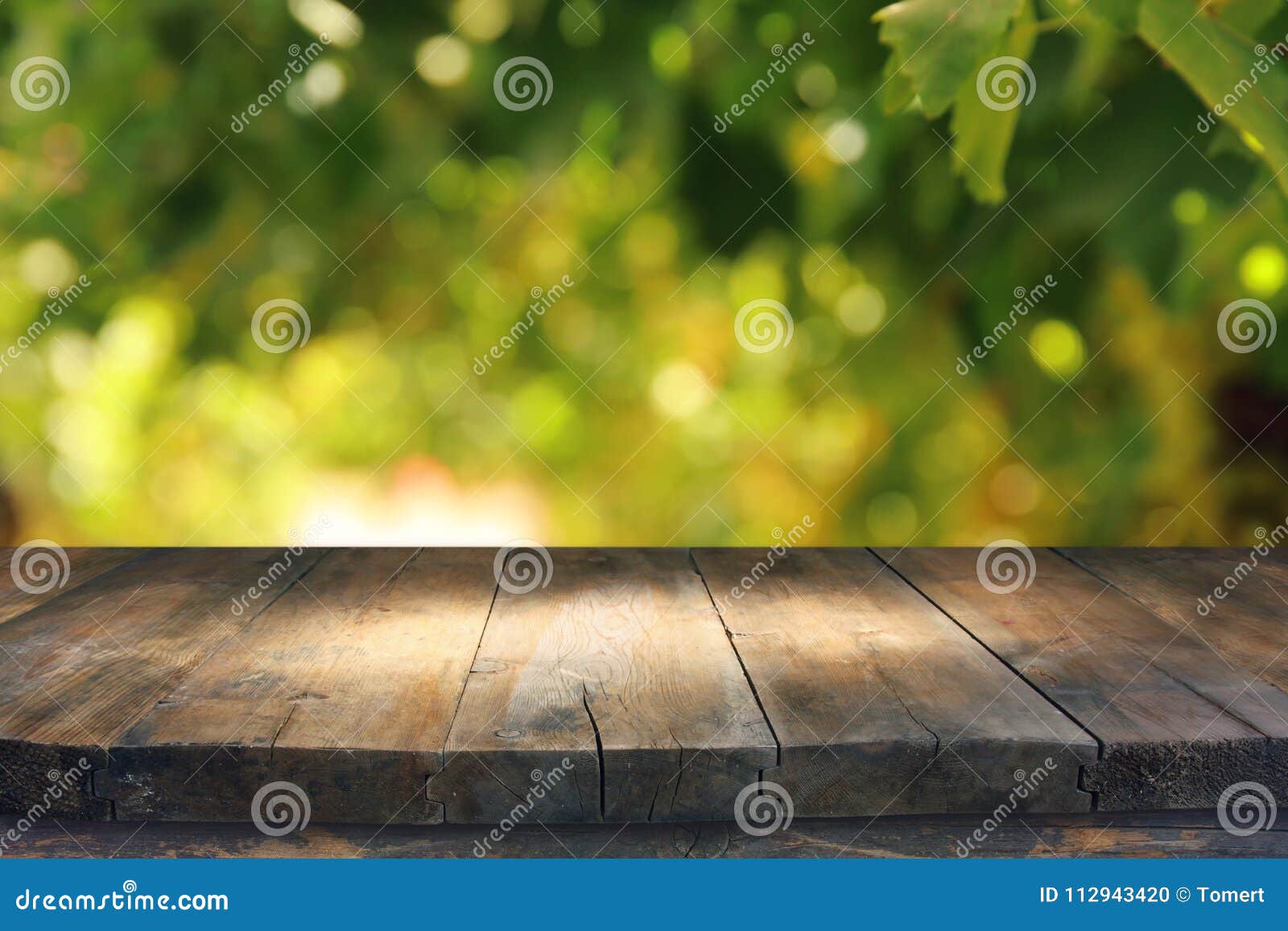 empty rustic table in front of green spring abstract bokeh background. product display and picnic concept.