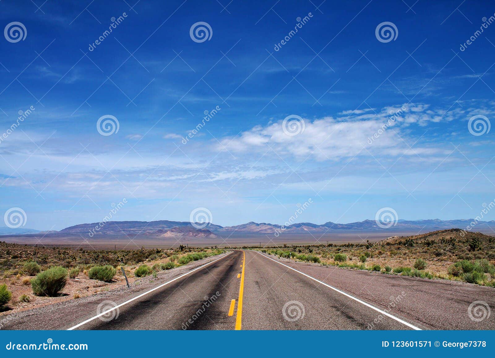 empty desert road with open sky and distant mountains in nevada