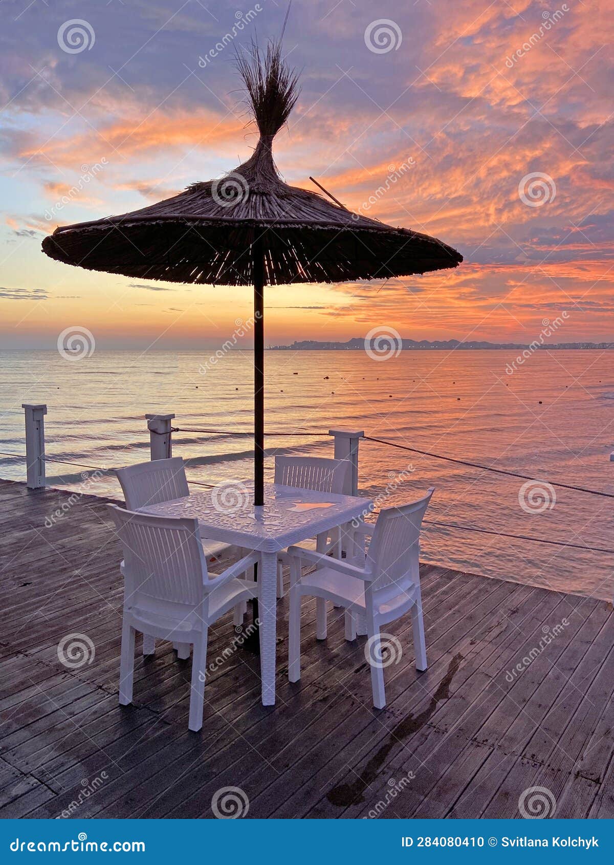 Empty Table and Chairs Under Beach Umbrella on a Beautiful Sunset Sea