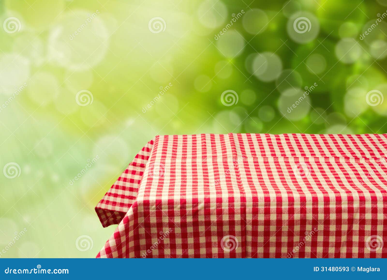 empty table with red checked tablecloth over green bokeh background.