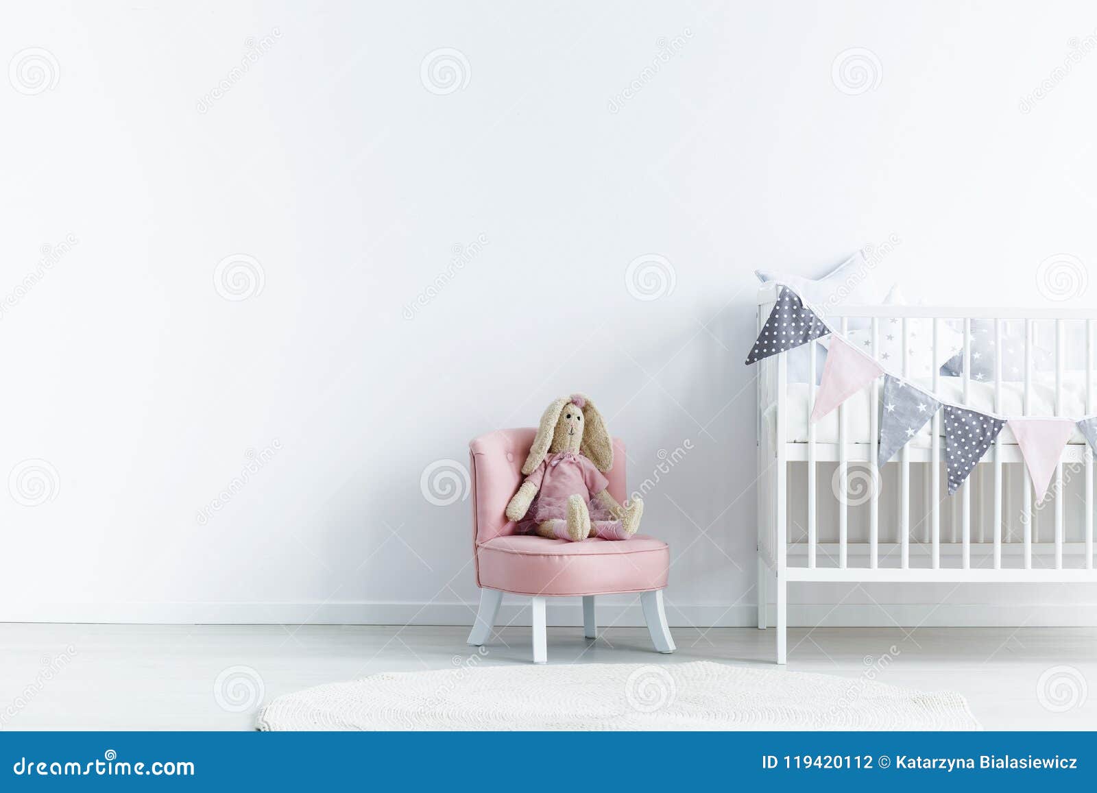 empty wall next a to chair with a rabbit and crib with triangles