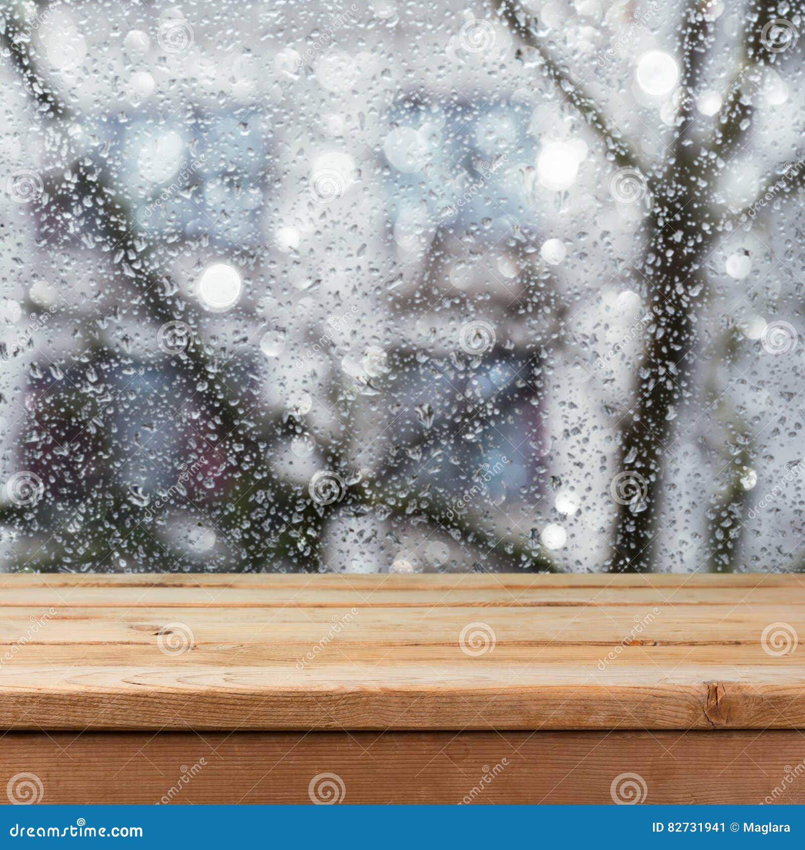 empty wooden deck table over wet glass window. rainy weather concept.