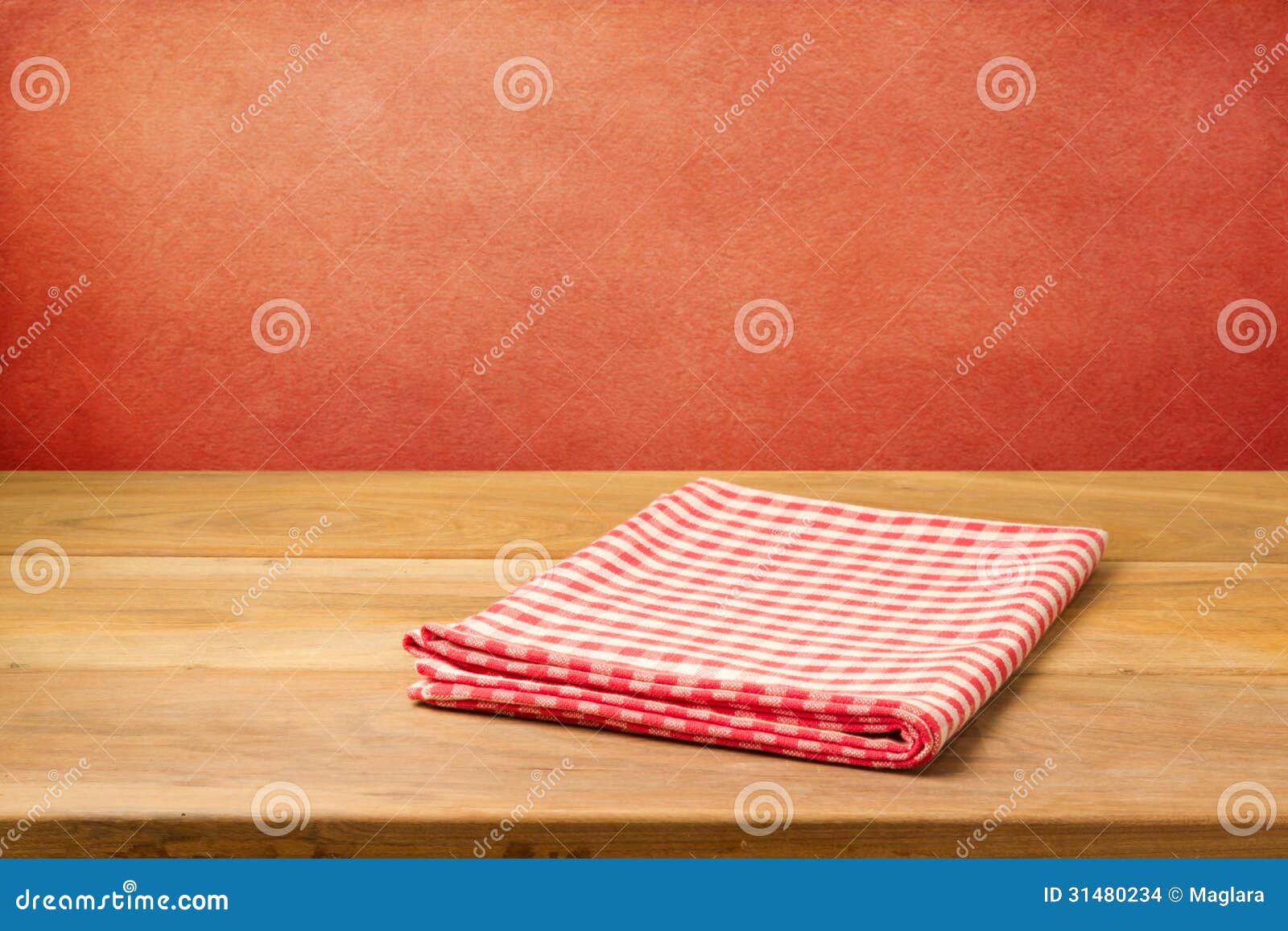 empty wooden table with checked tablecloth over grunge red concrete wall.