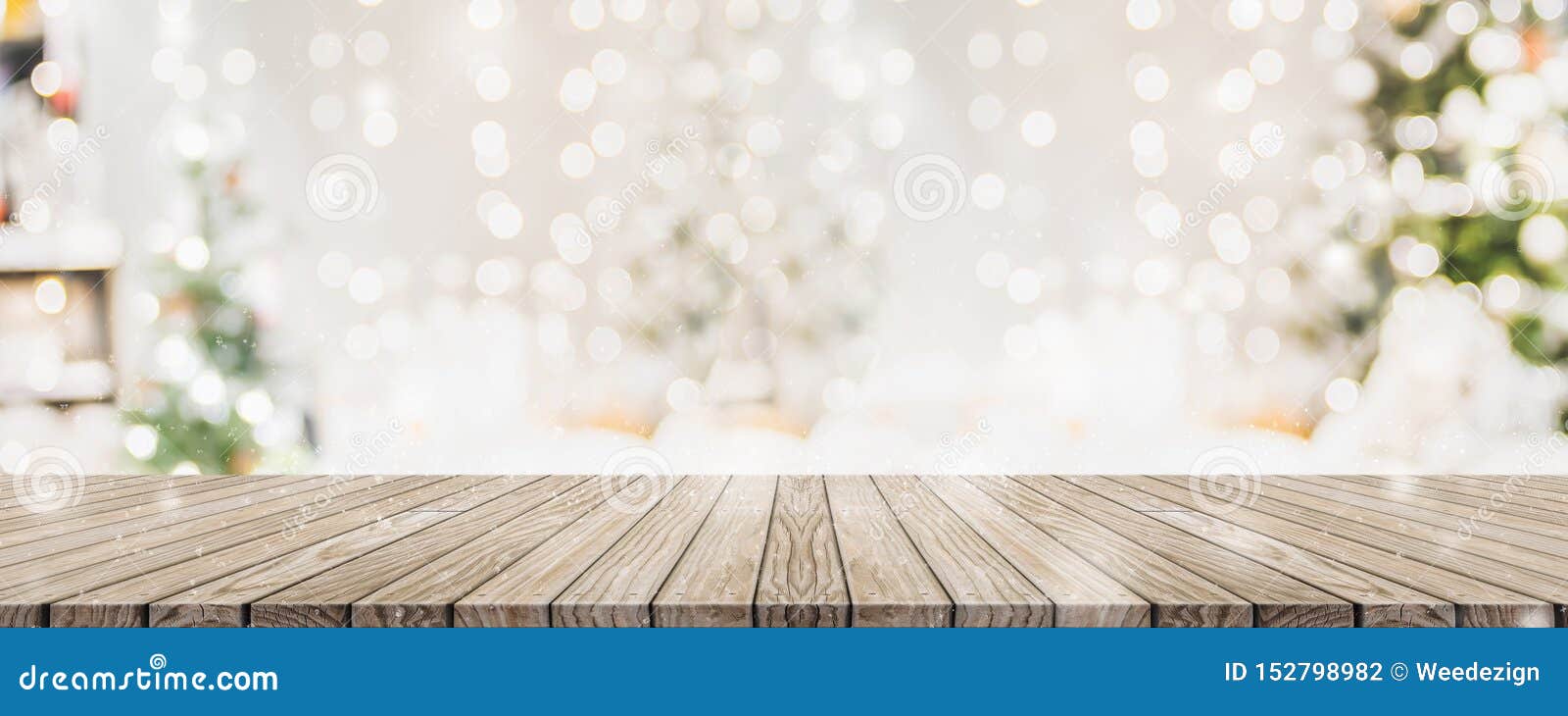 empty woooden table top with abstract warm living room decor with christmas tree string light blur background with snow,holiday