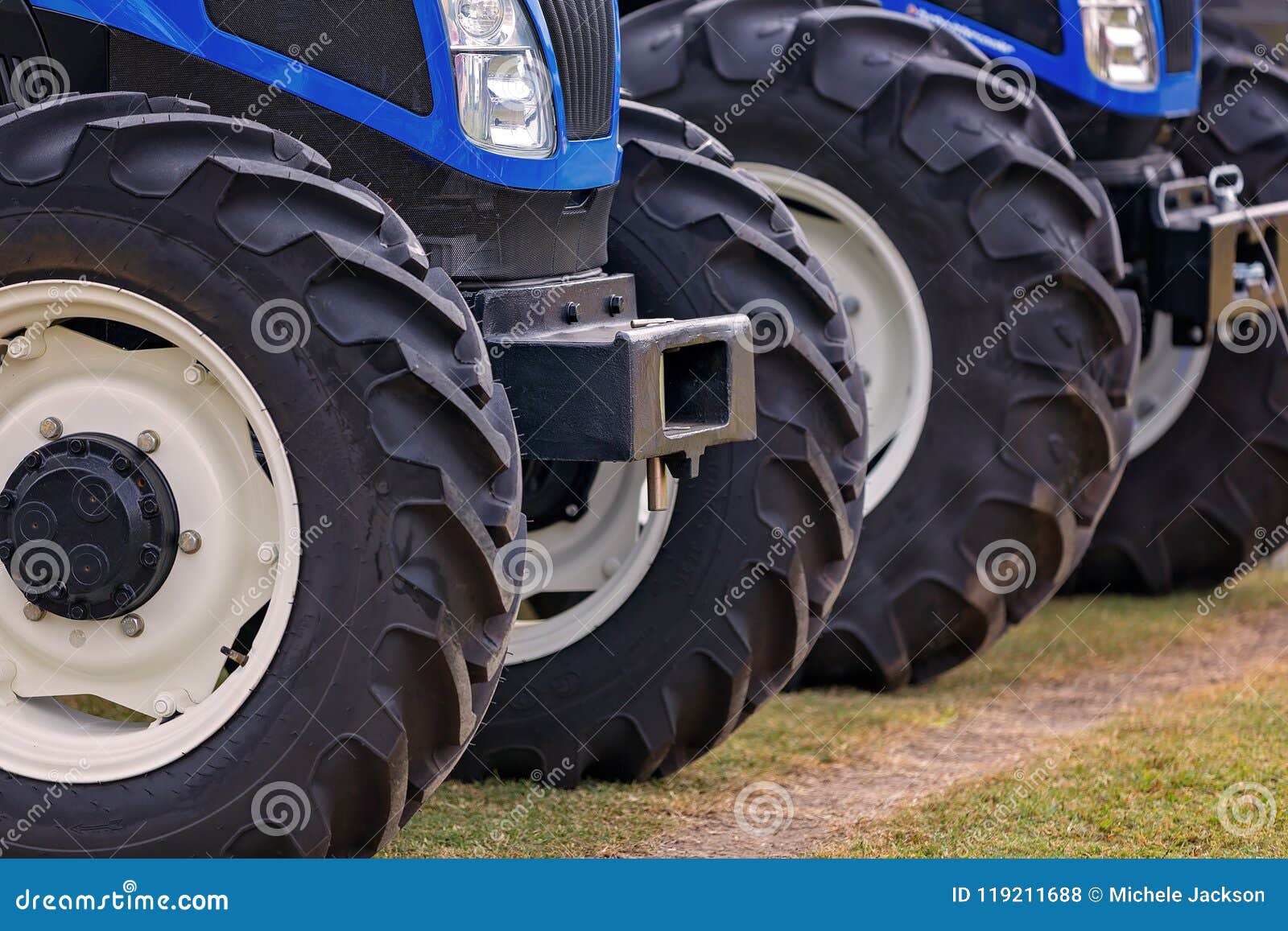 En rad av traktorgummihjul uppställda på skärm. En rad av traktorer ställde upp på skärm på en jordbruks- show för land