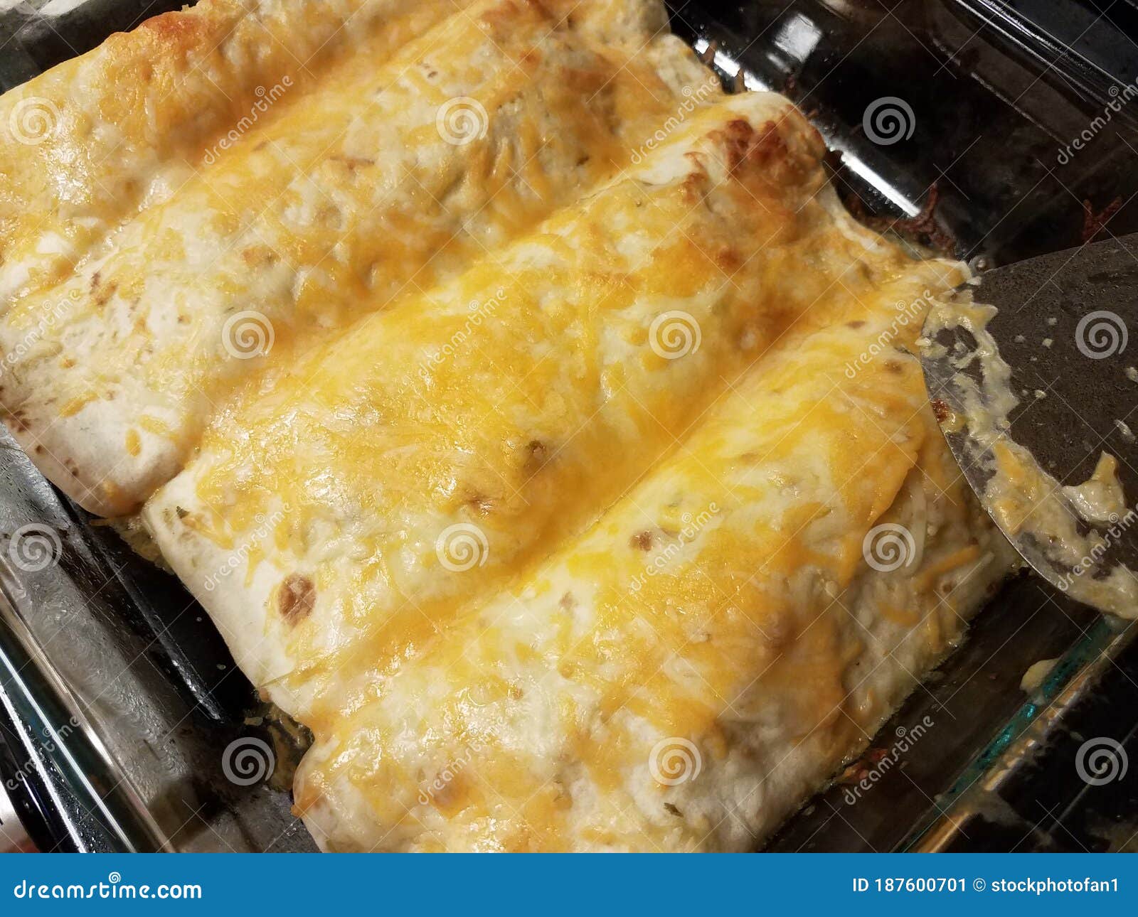 Enchiladas with Cheese in Glass Pan on Stove with Spatula Stock Image