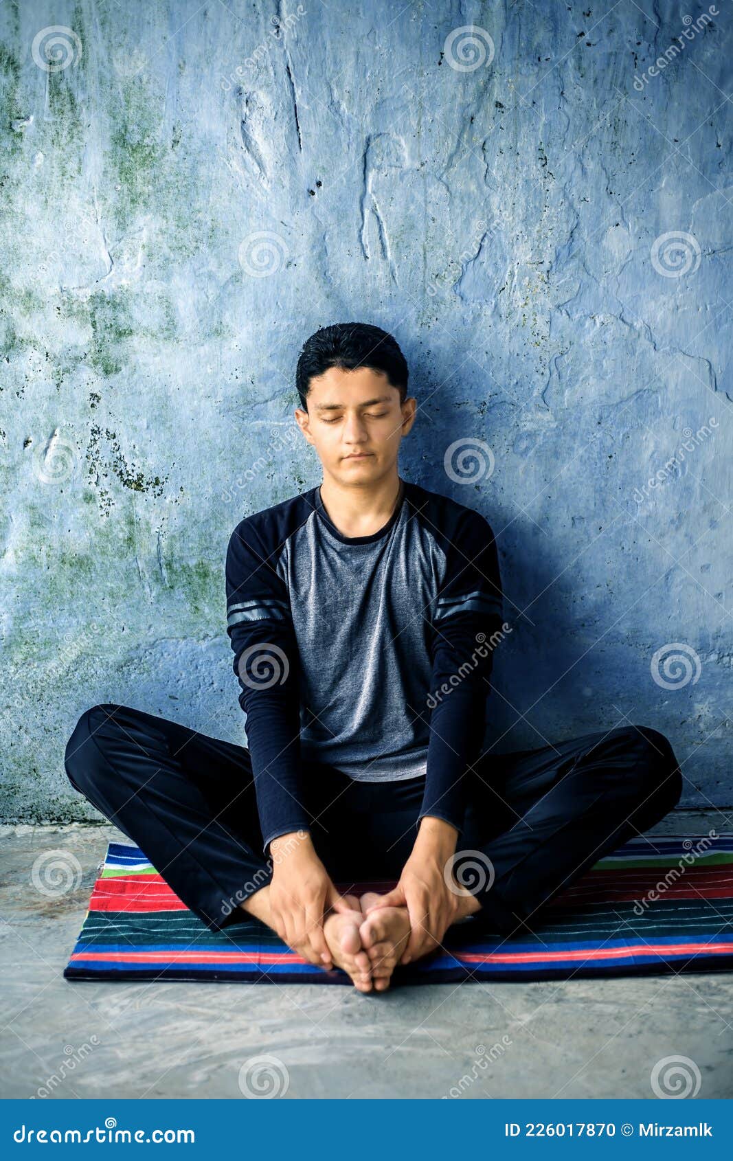 an energetic young caucasian teenager doing bound angle pose or bah-dah cone-ahs-anna pose practice.