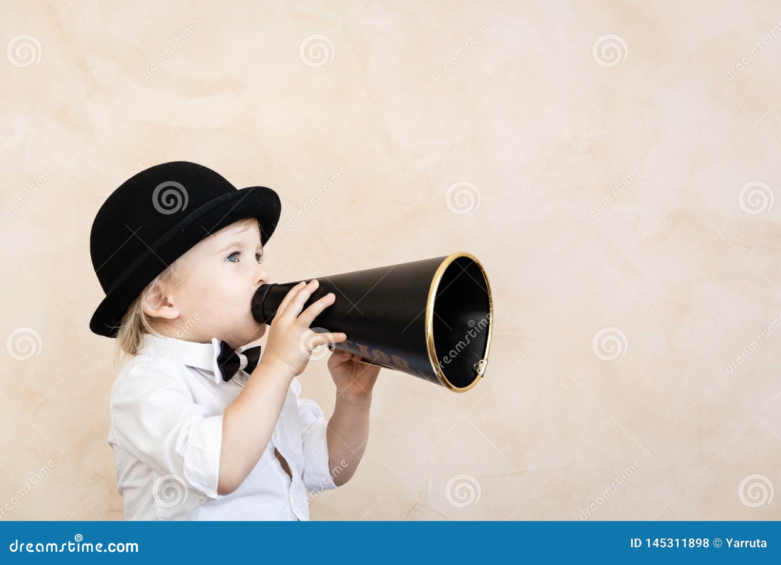 Funny child playing with black retro megaphone. Funny child playing at home. Kid shouting through vintage megaphone. Communication and retro cinema concept